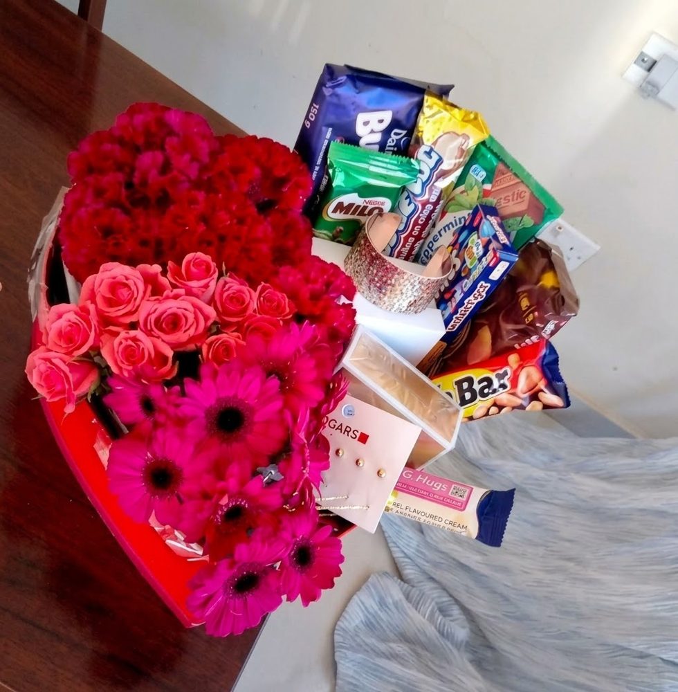 Heart-shaped box of pink roses, magenta gerberas and red carnations with chocolates and keepsake gifts